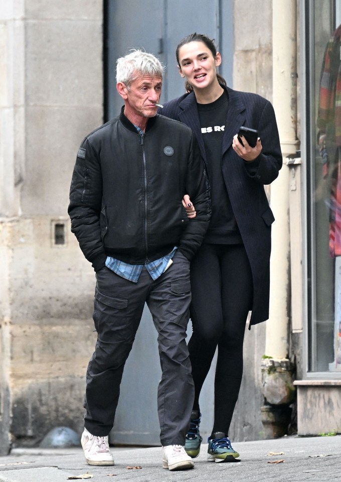 a man and a woman are walking down a street and the woman is wearing a sweatshirt that says bs rc