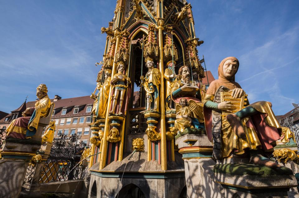 a statue of a man holding a book is surrounded by other statues