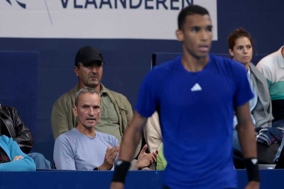 a man in a blue adidas shirt watches a tennis match