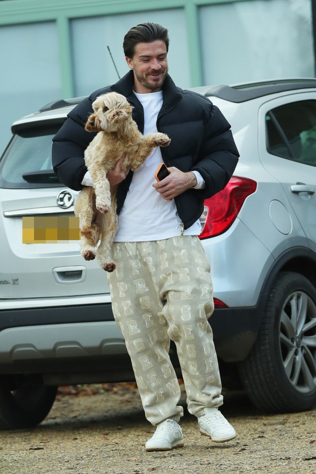 a man holding a small dog in front of a vauxhall car