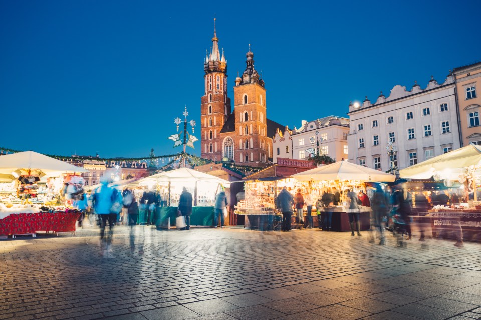 a blurred image of a christmas market with a church in the background