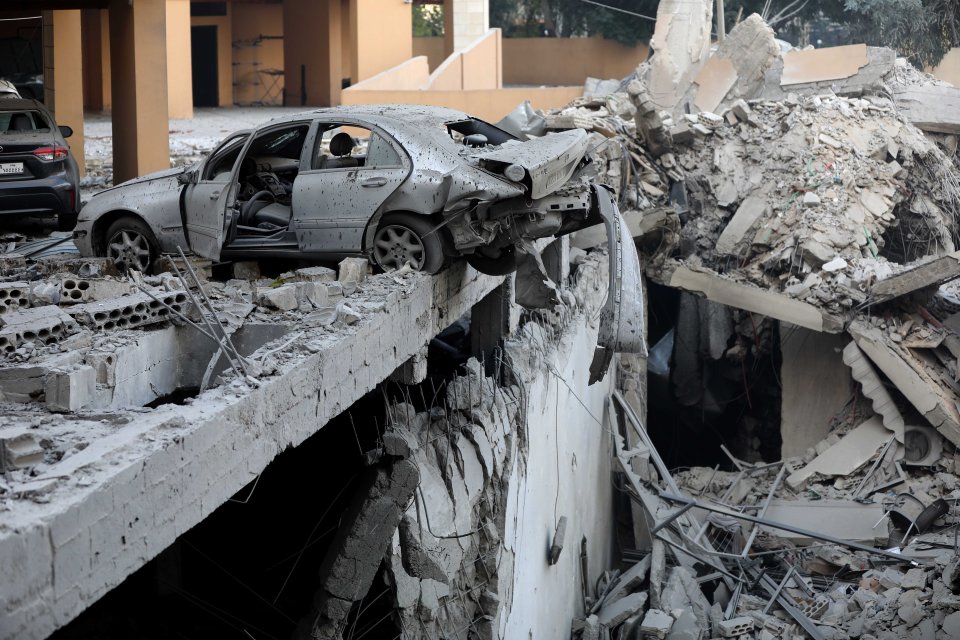 a car with the door open is sitting on top of a pile of rubble