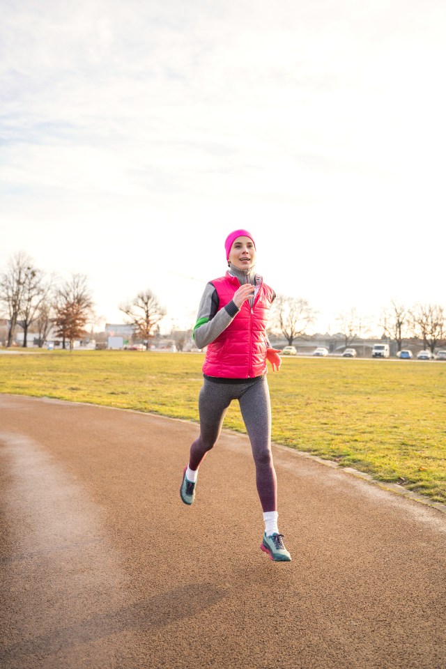 a woman in a pink vest is running on a track