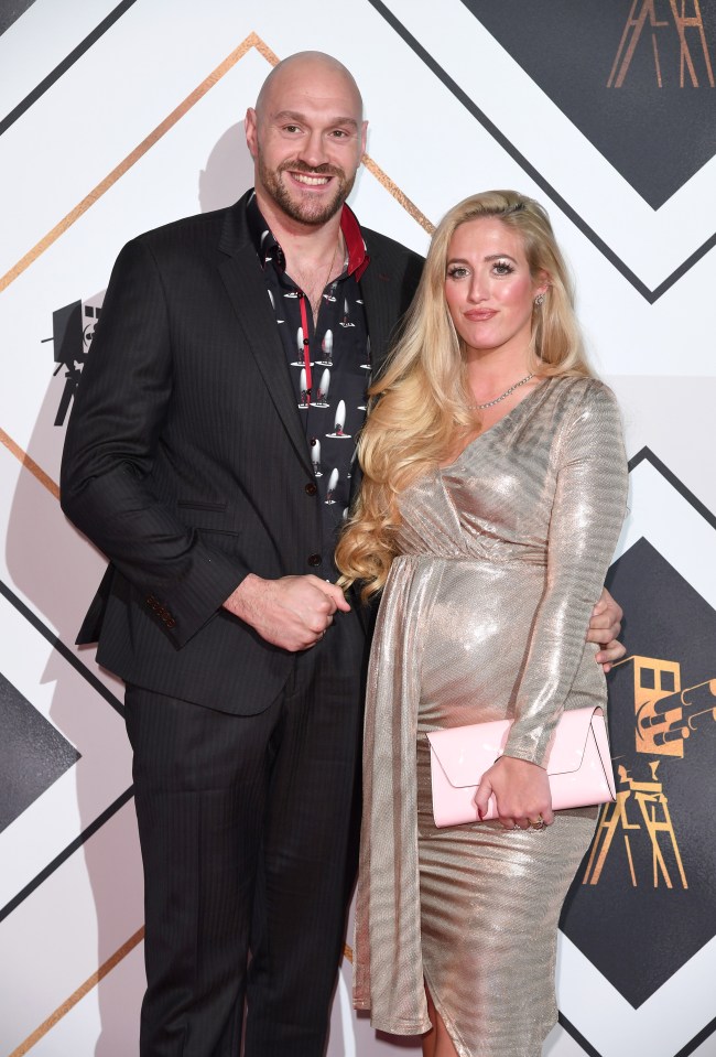 a man in a suit stands next to a woman in a gold dress