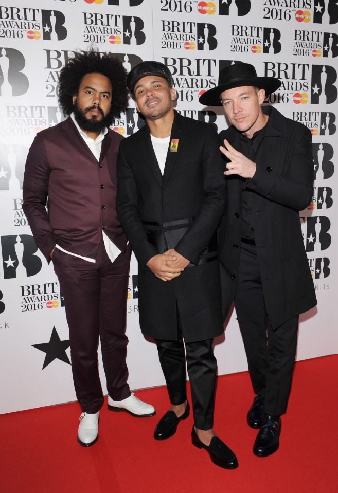 three men are standing on a red carpet at the brit awards