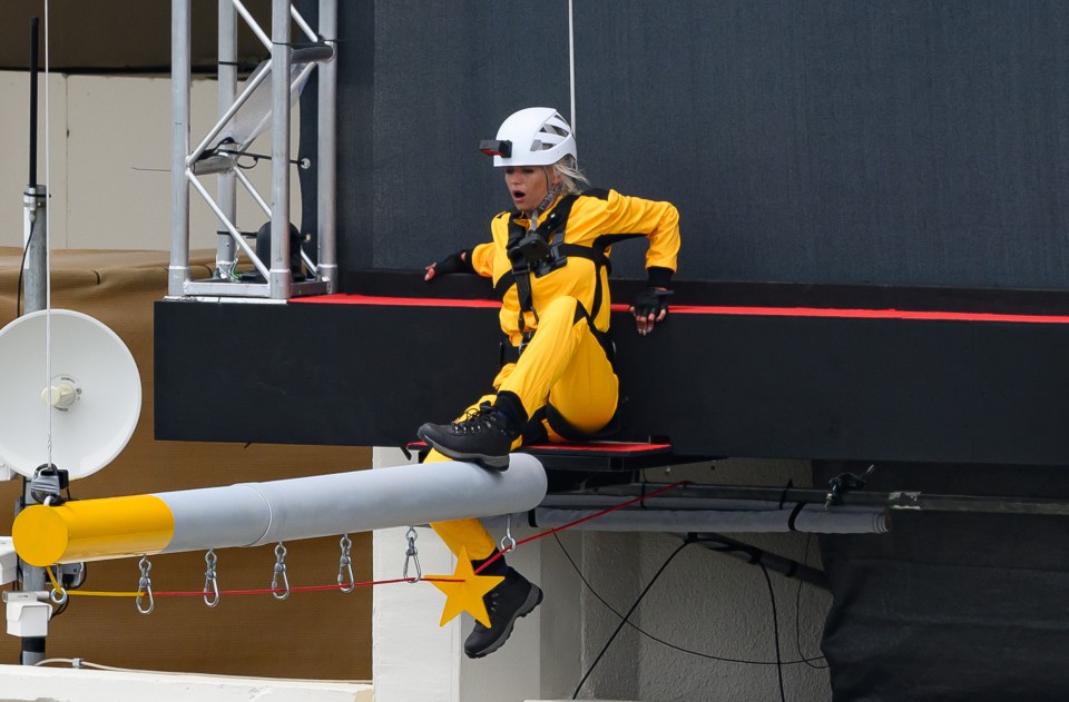 a person in a yellow suit and white helmet is sitting on a pole