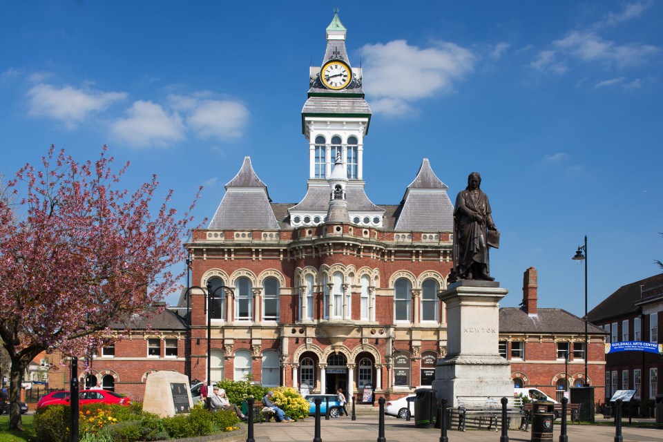 a large brick building with a clock tower and a statue in front of it that says bolton