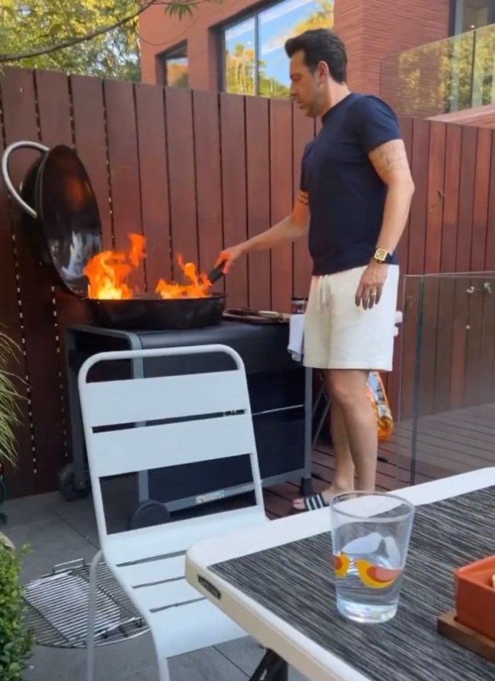 a man cooking on a grill with a watch on his wrist