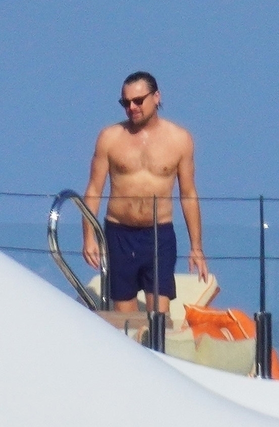 a shirtless man in blue shorts is standing on a boat