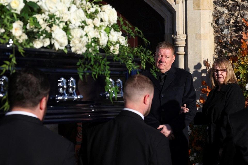 a man carrying a black coffin with the letters aa on it