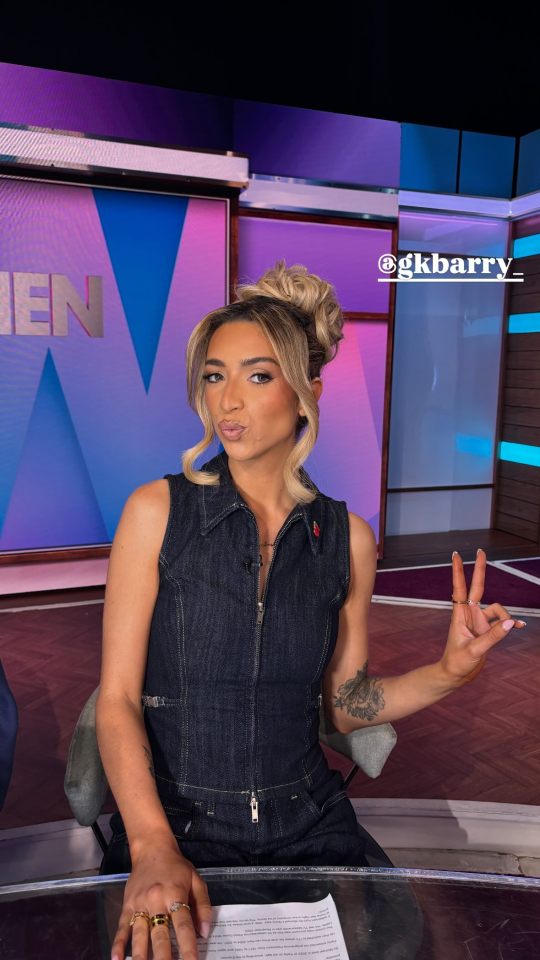 a woman in a denim dress is giving a peace sign
