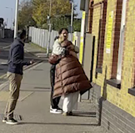 a man is talking on a cell phone while standing next to a woman on a sidewalk .