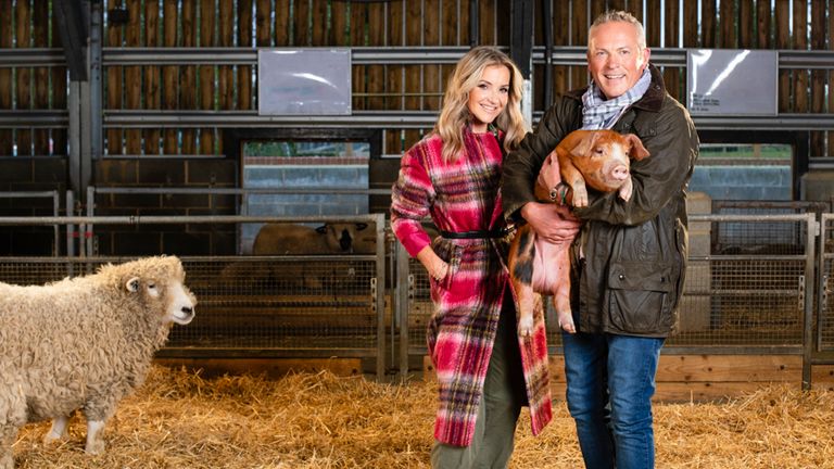 a man and woman holding a pig and a sheep in a barn
