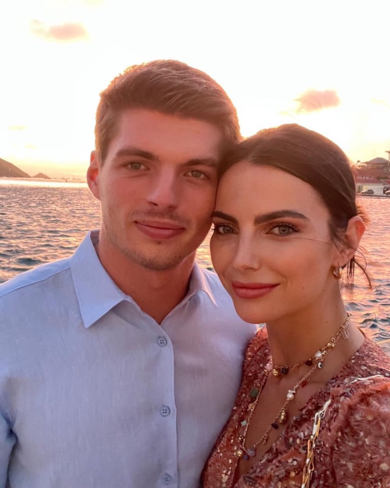 a man and a woman pose for a picture in front of a body of water
