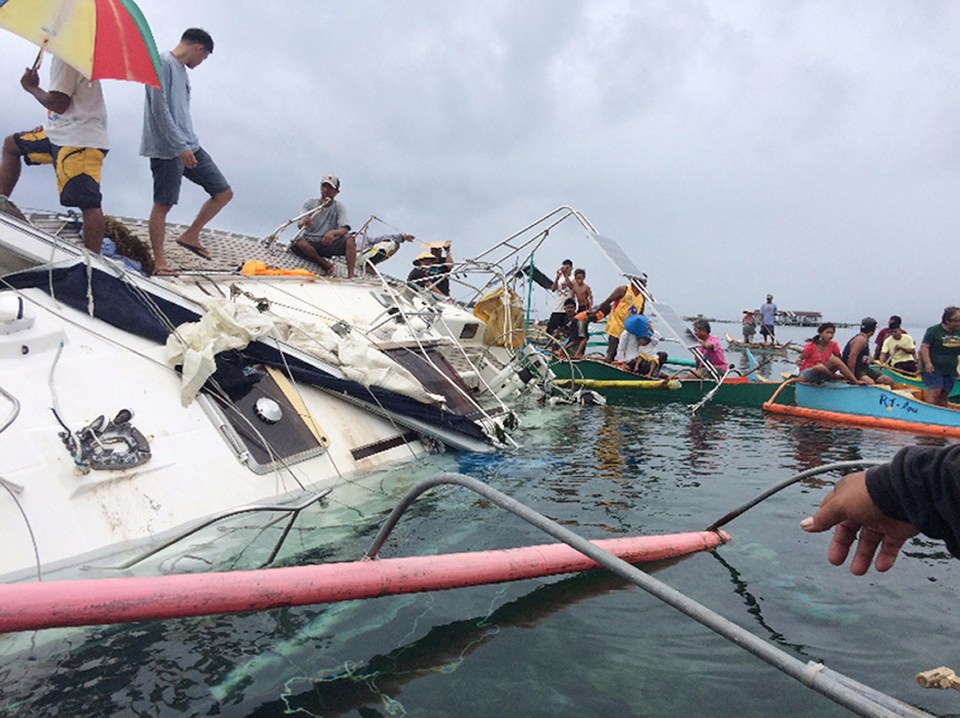 Police, coast guard, and fishermen inspecting a yacht after a sailor was found dead aboard.