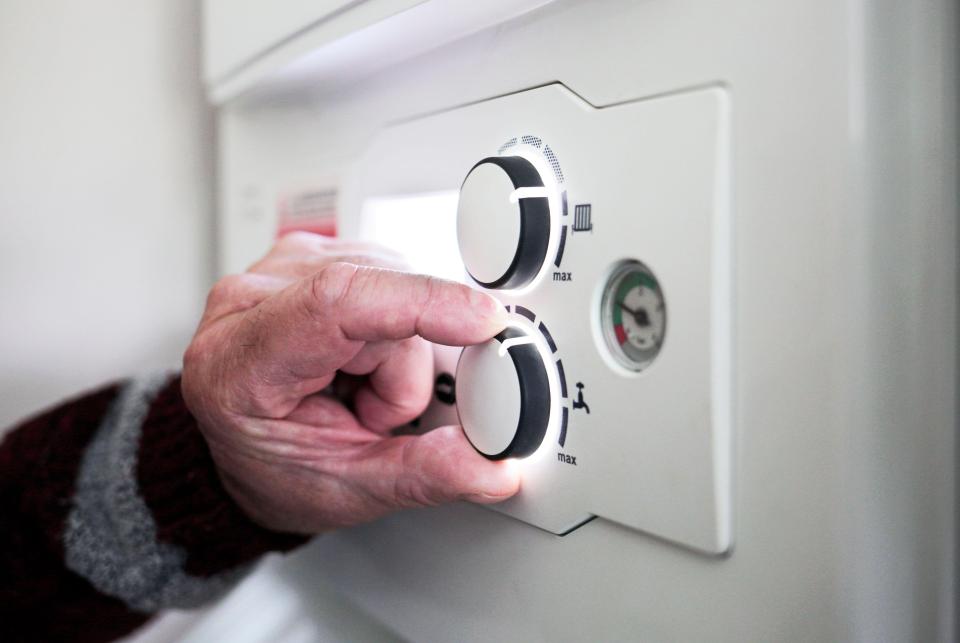 A pensioner's hand adjusting the temperature control on a combi boiler.