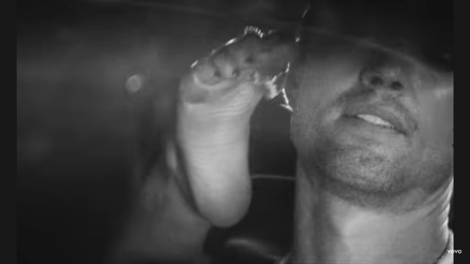 Close-up of a foot and a man's face in black and white.