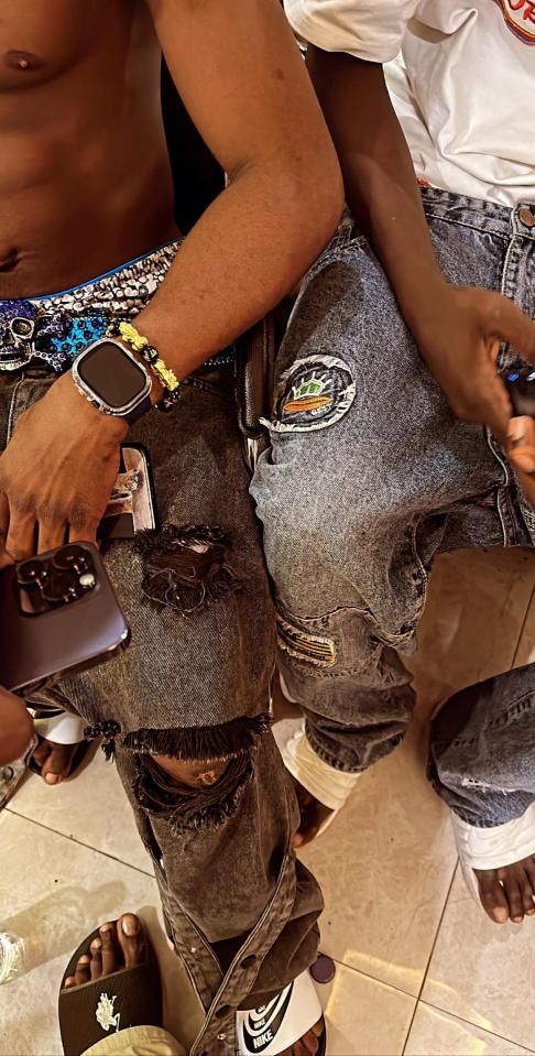 Close-up of two people wearing ripped jeans and sandals.
