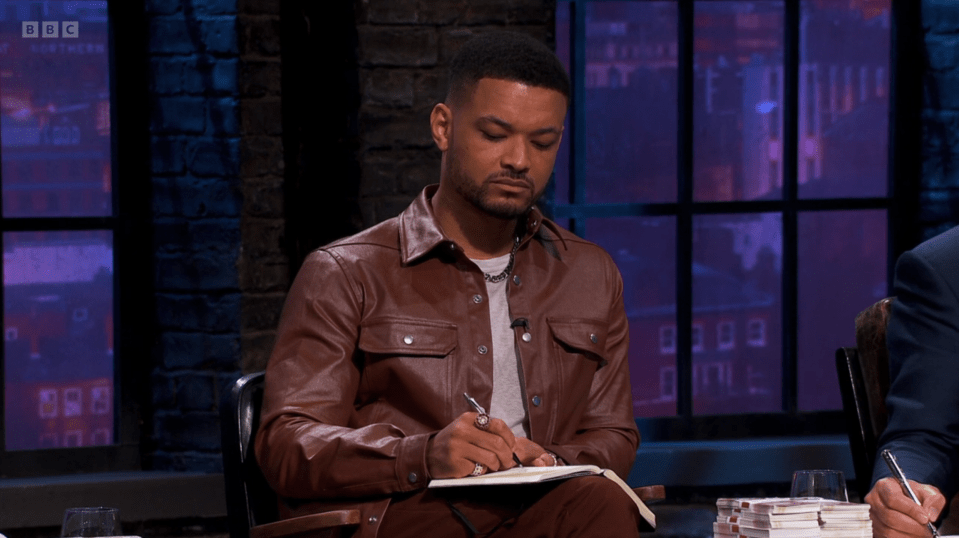 Man in brown leather jacket writing in a notebook.