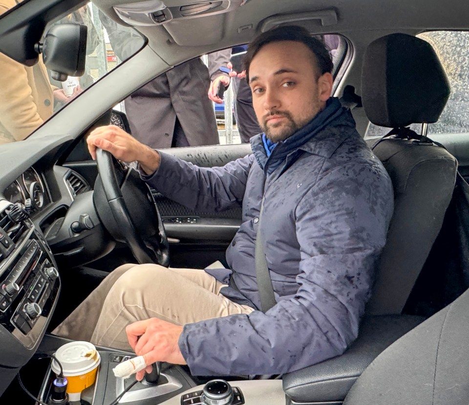 Man with bandaged finger sitting in a car.