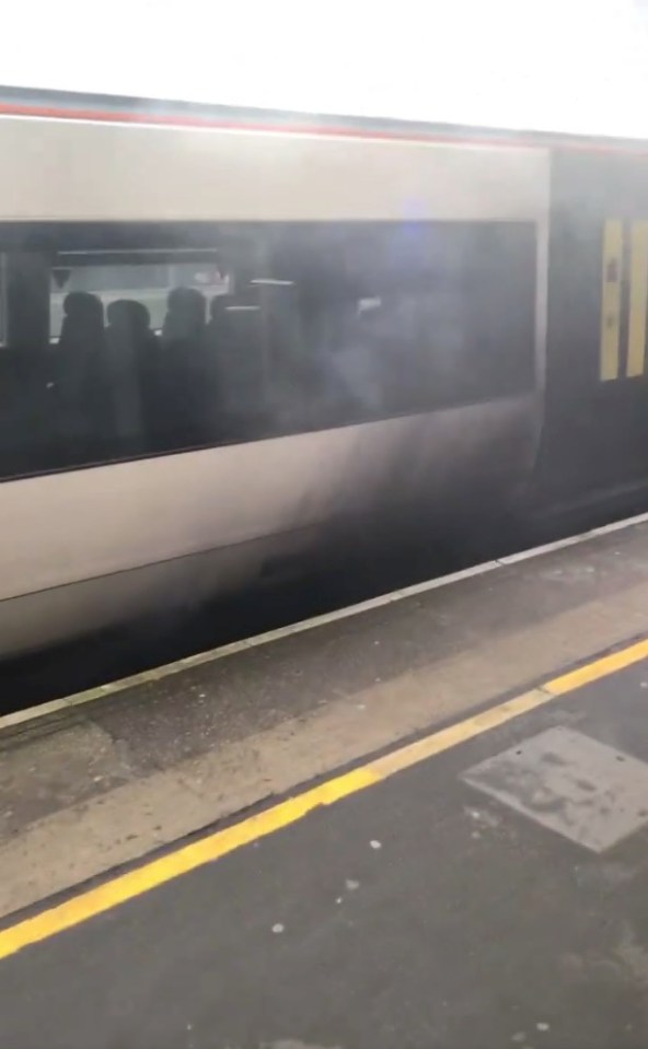 Smoke billowing from a train at Gatwick Airport railway station.