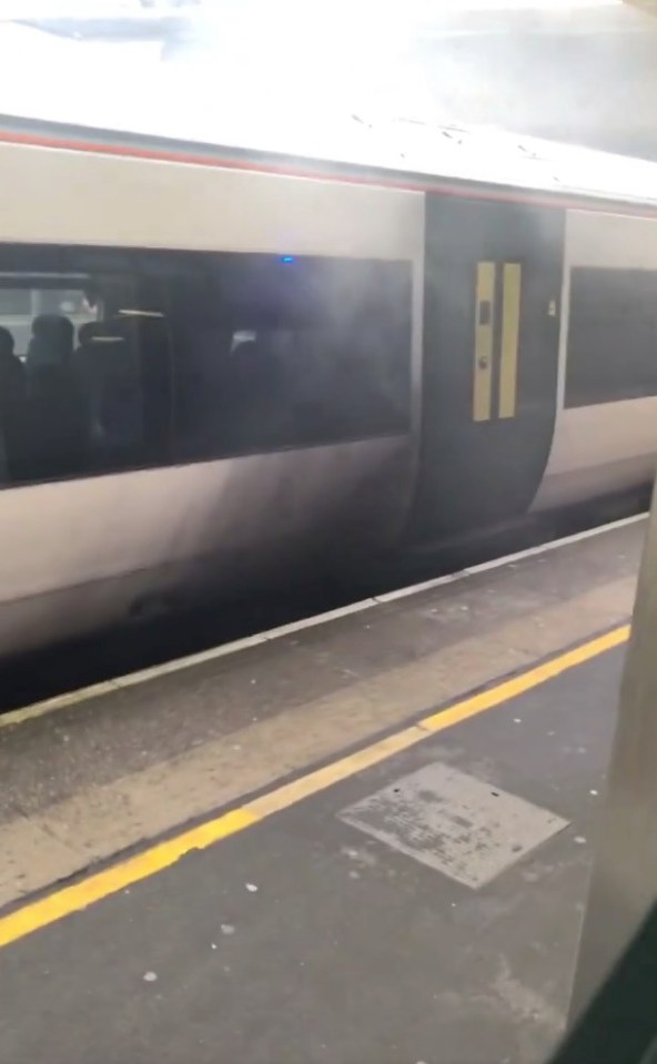 Smoke billowing from a train at Gatwick Airport railway station.
