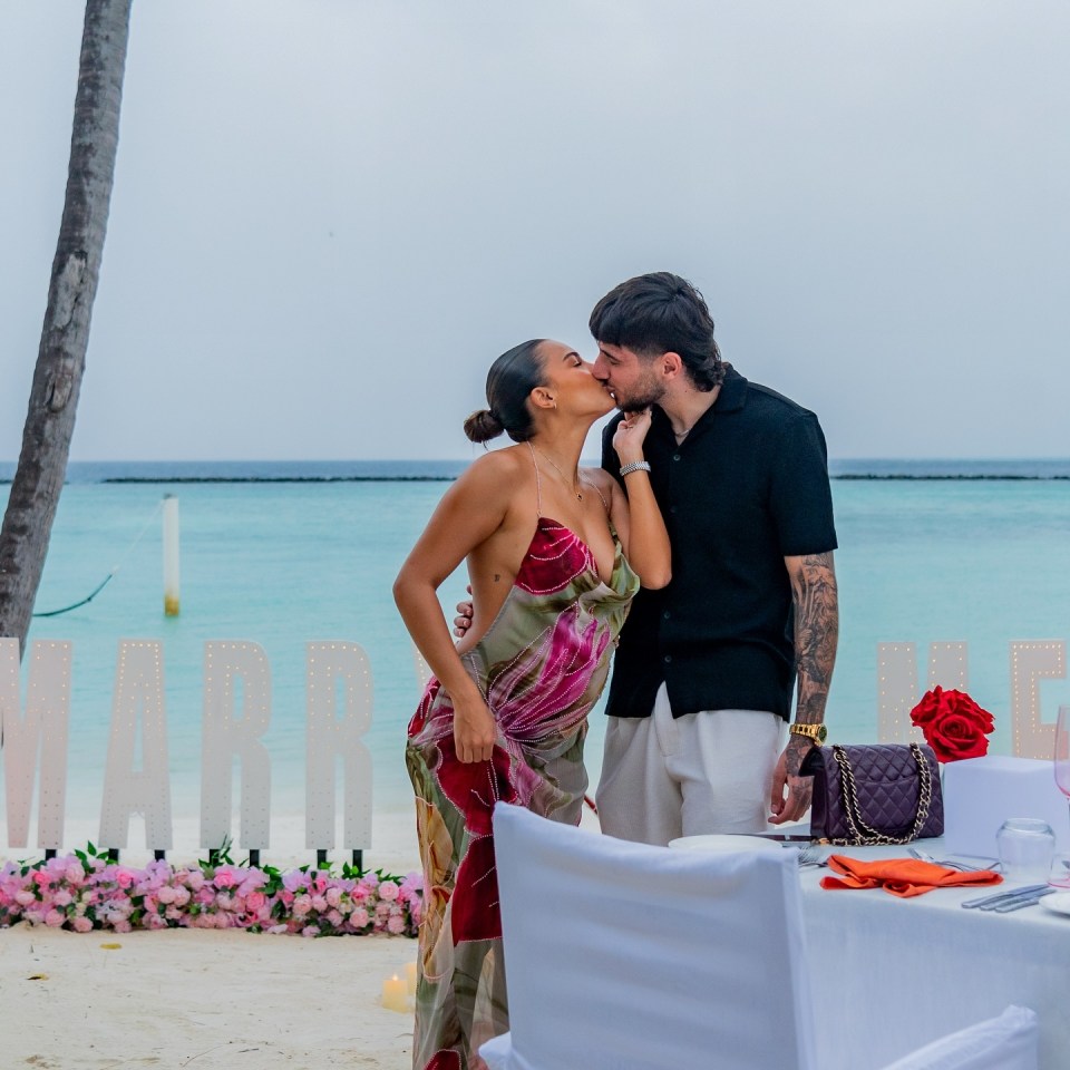 Couple kissing at beach proposal.