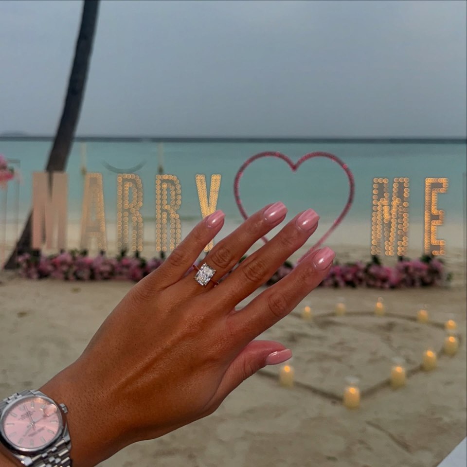 Beach proposal with "Marry Me" sign and engagement ring.