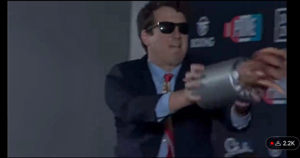Man in suit throwing hot dogs at another man.