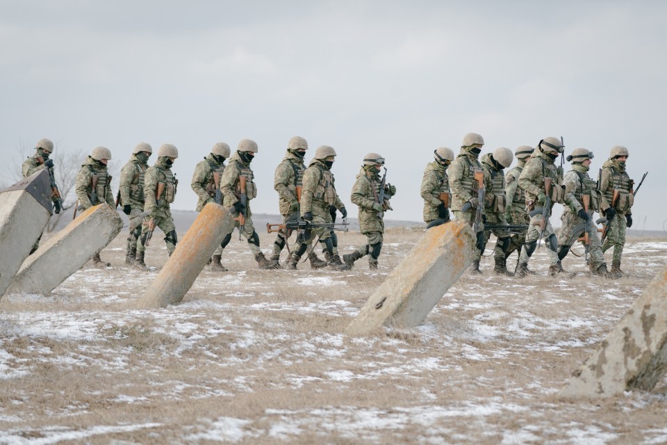 Romanian soldiers walking in a line during a military exercise.