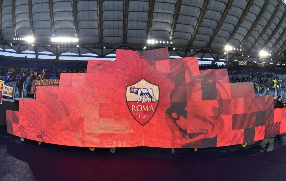 AS Roma logo displayed on a large screen at a stadium.
