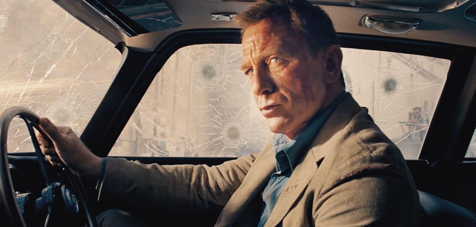 Daniel Craig in No Time to Die, driving a car with a shattered windshield.