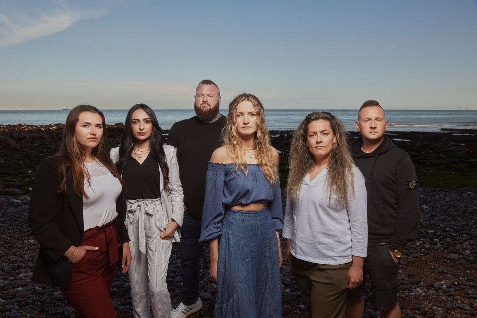 Photo of six people standing on a beach, facing the camera.  They appear to be participants in a documentary about immigration.