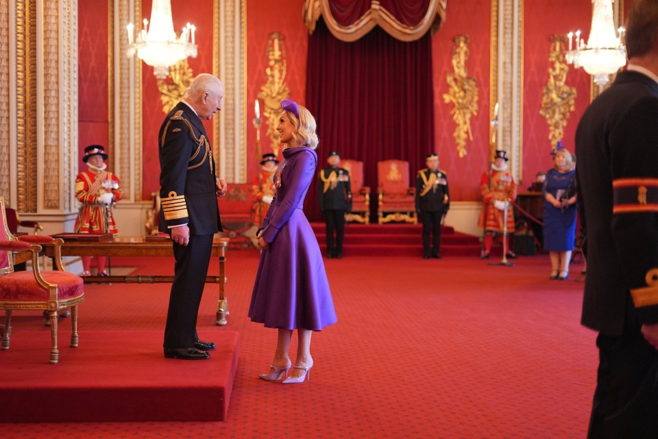 King Charles III bestowing an MBE on Amy Dowden at Buckingham Palace.