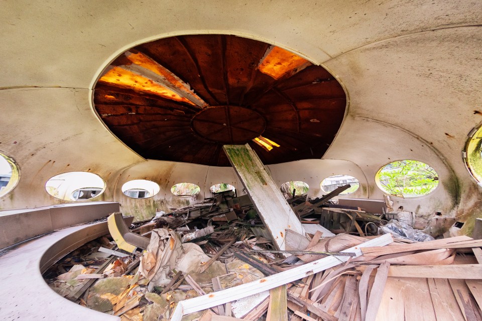Interior of a dilapidated UFO-shaped building filled with debris.