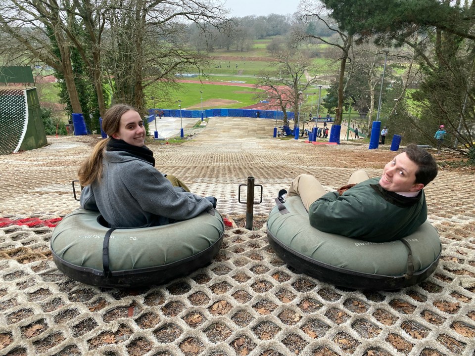 Two people in snow tubes at the top of a snow tubing hill.