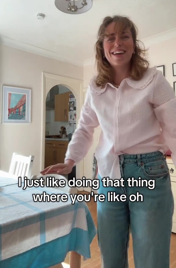 Woman in pink pajama top and jeans in a dining room.