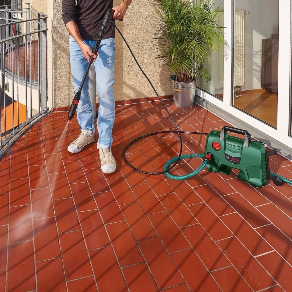 Person using a Bosch pressure washer to clean a patio.