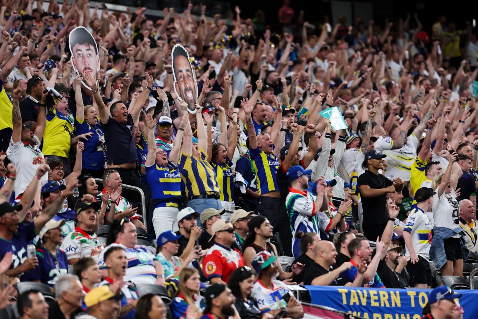Excited fans cheering at a Wigan Warriors vs Warrington Wolves rugby match.