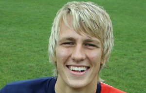 Smiling young man in a red soccer jersey.