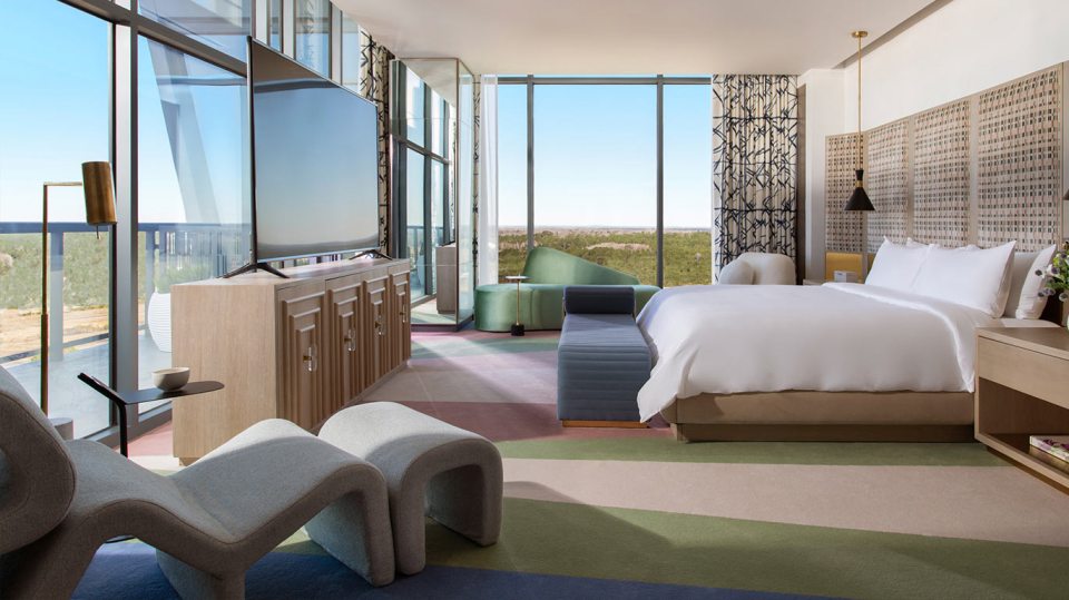 Hotel suite with a king-size bed and floor-to-ceiling windows.