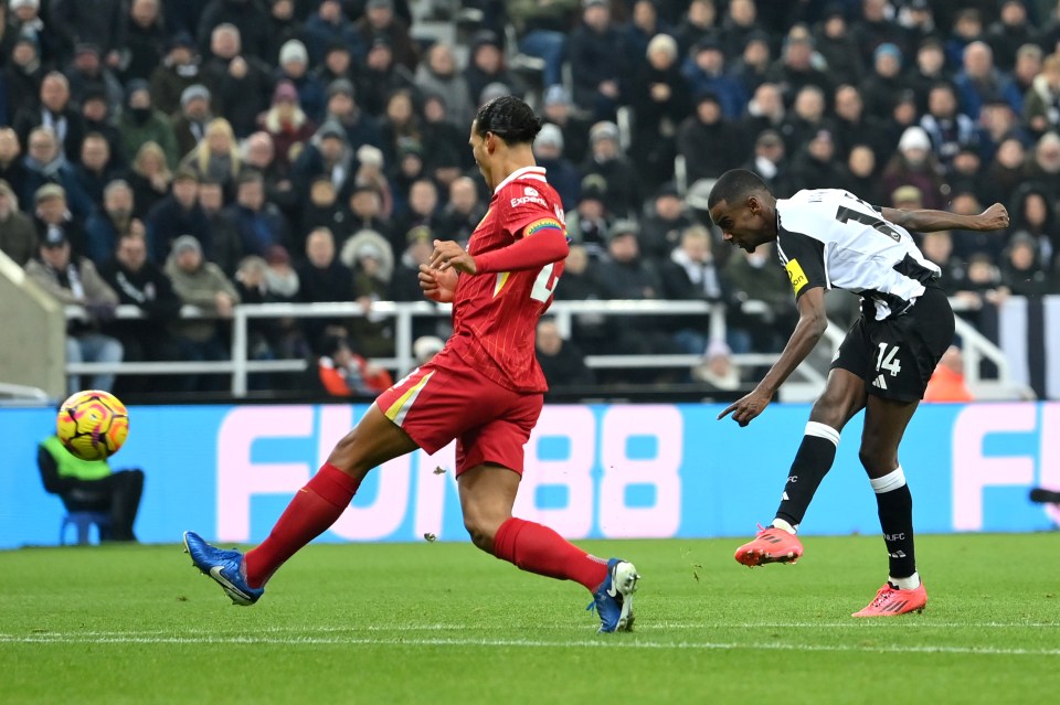Alexander Isak of Newcastle United scoring a goal while Virgil van Dijk of Liverpool defends.