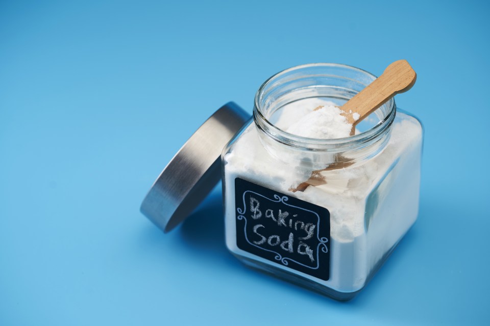 Baking soda in a glass jar with a wooden scoop.