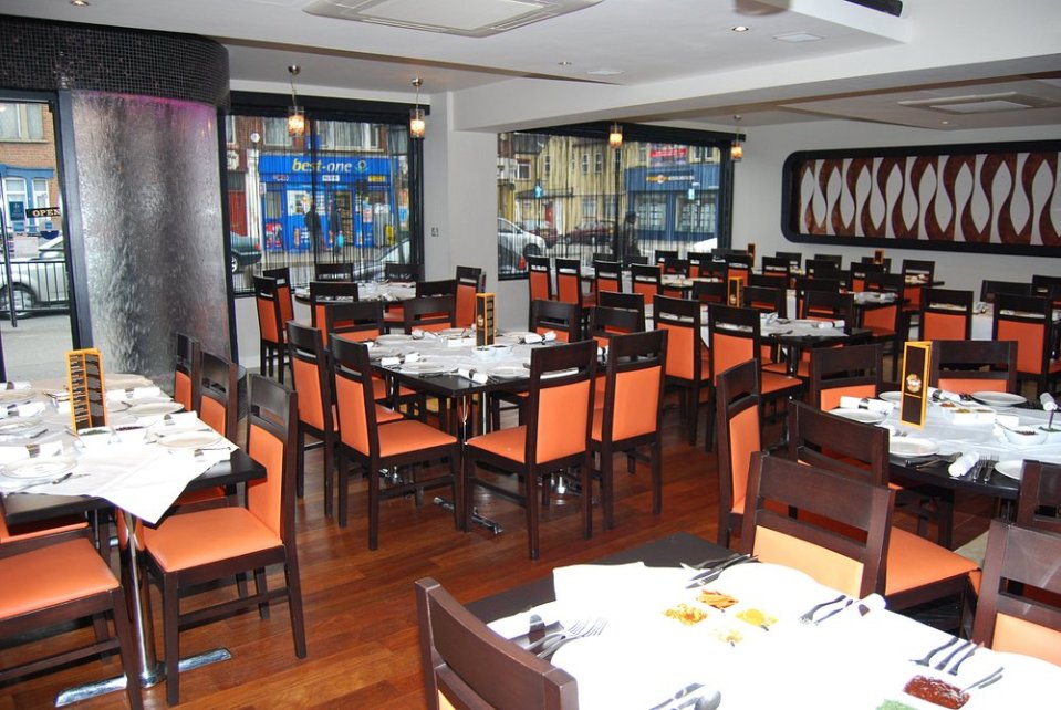 Interior view of a restaurant with many tables and orange chairs.