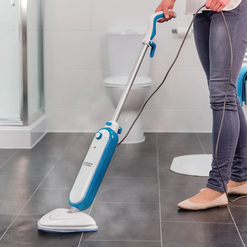 Person using a steam mop to clean a tile floor.