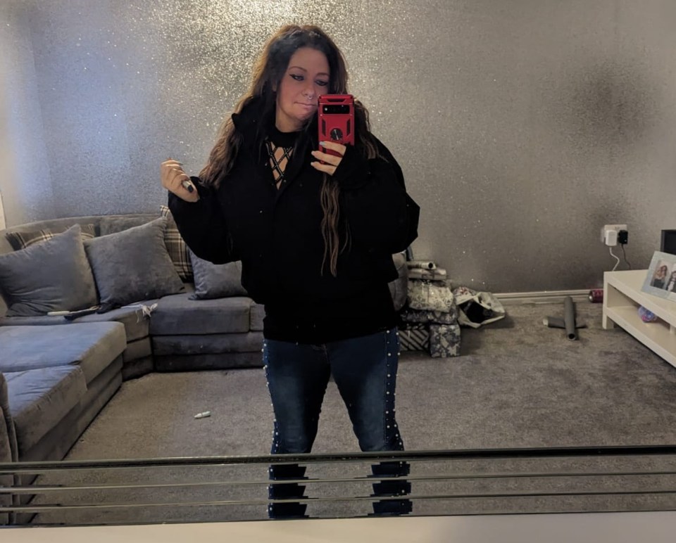 Mirror selfie of a woman in a black sweater and jeans.