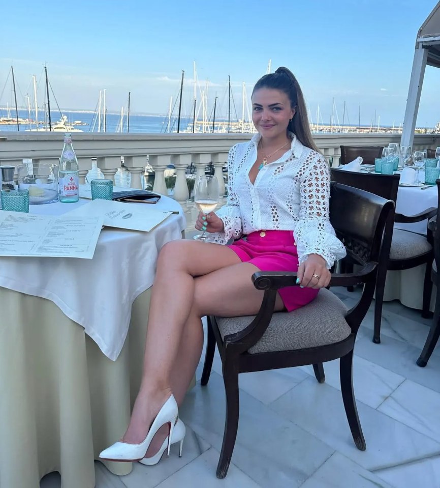 Woman sitting at an outdoor restaurant table with a harbor view.