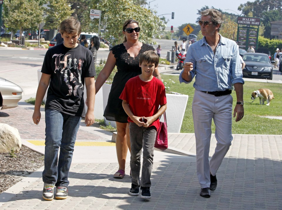 Pierce Brosnan, Keely Shaye Smith, and their sons walking down a sidewalk.