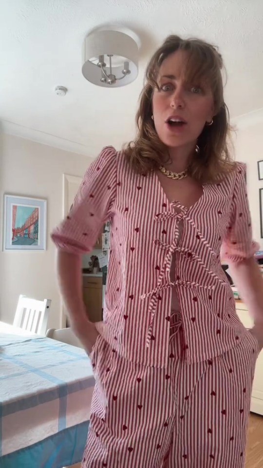 Woman modeling red and white striped pajamas with small hearts.