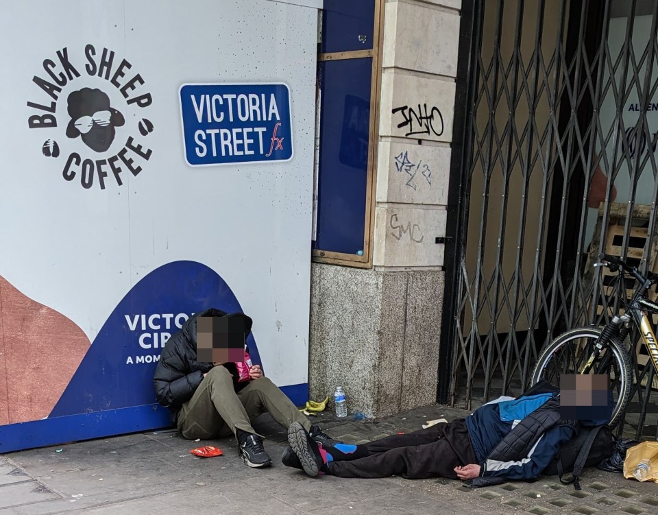 Two people sleeping on the ground near Victoria Station in London.